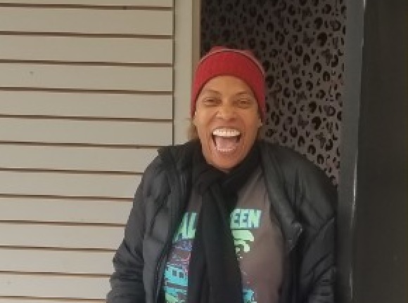 Community in action: smiling volunteer in winter wear outside a program location
