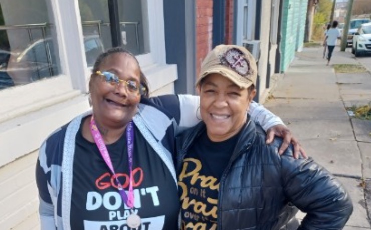 Community in action: neighbors smiling together on a sidewalk outside a brick building