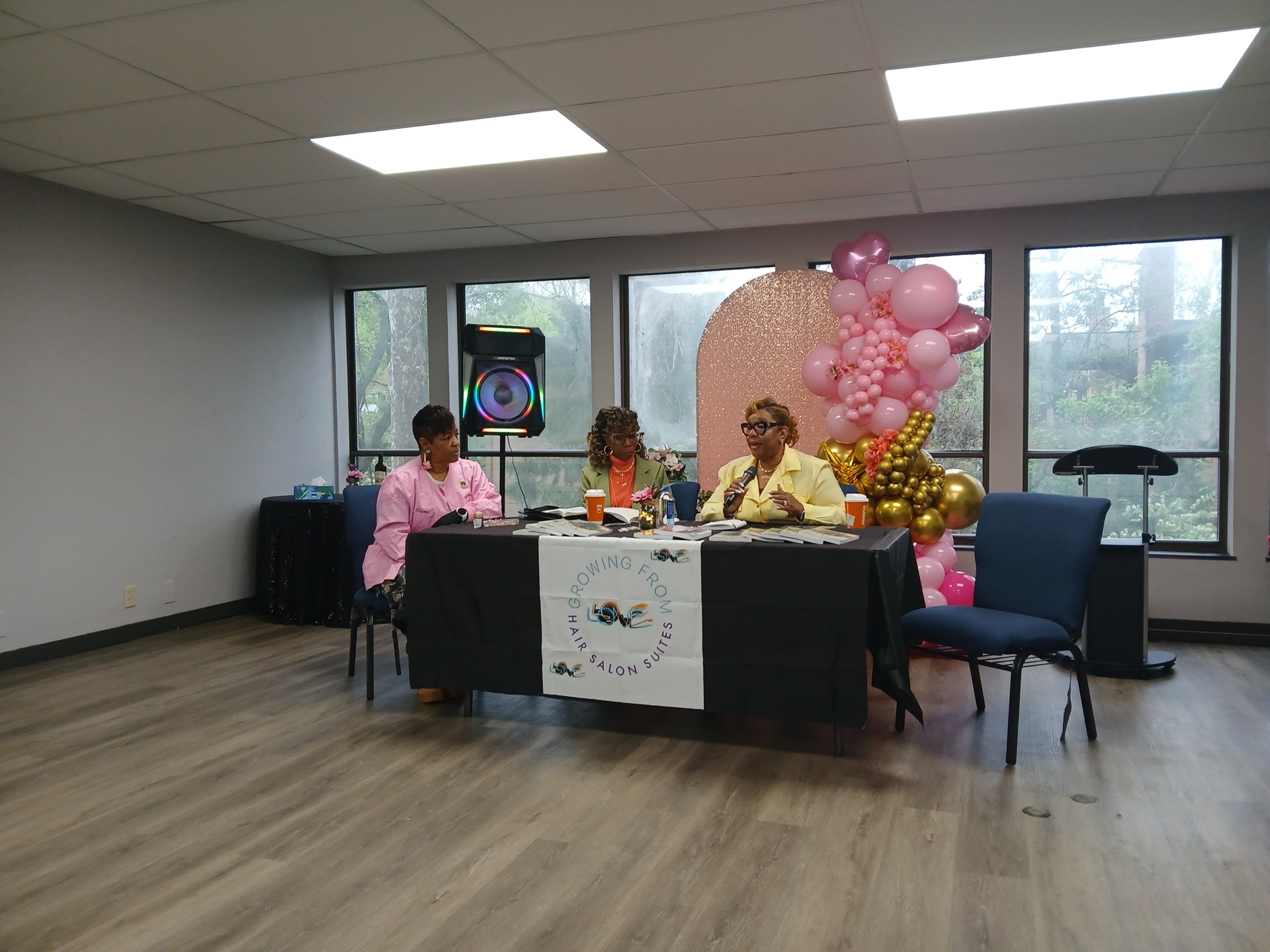 Growing From Love Hair Salon Suites community event: panel discussion with microphone and table display