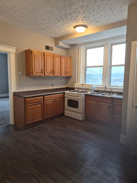 Shared living unit: L-shaped kitchen with cabinets and sink under windows