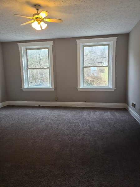 Shared living unit: empty room with windows and ceiling fan